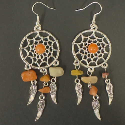 Pair of dreamcatcher earrings with orange and beige stones on a dark background
