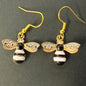Bee-shaped earrings with gold, black, and white design 