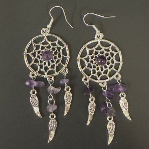 Pair of dreamcatcher earrings with purple beads and feathers on a dark background