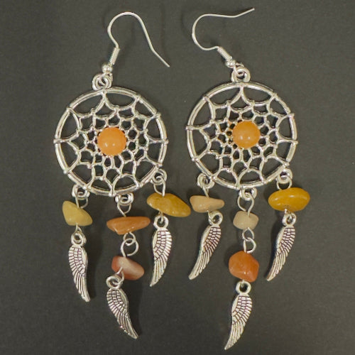 Pair of dreamcatcher earrings with orange and beige stones on a dark background